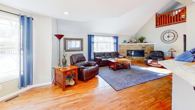 living room featuring visible vents, a stone fireplace, and wood finished floors