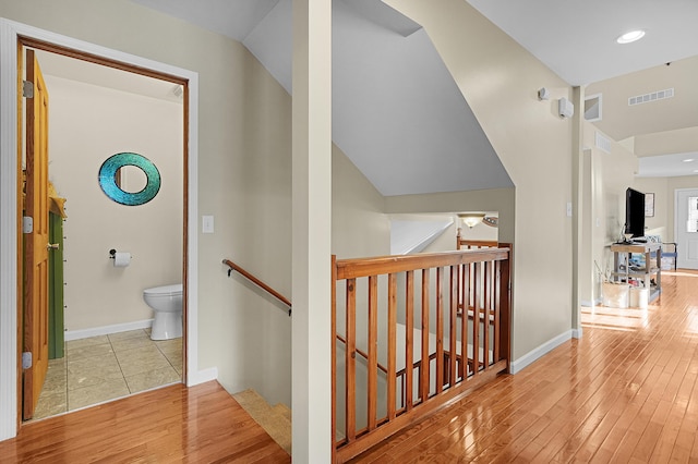 hallway featuring an upstairs landing, visible vents, baseboards, and wood-type flooring