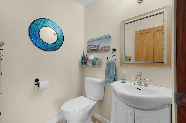 half bath with vanity, toilet, and baseboards