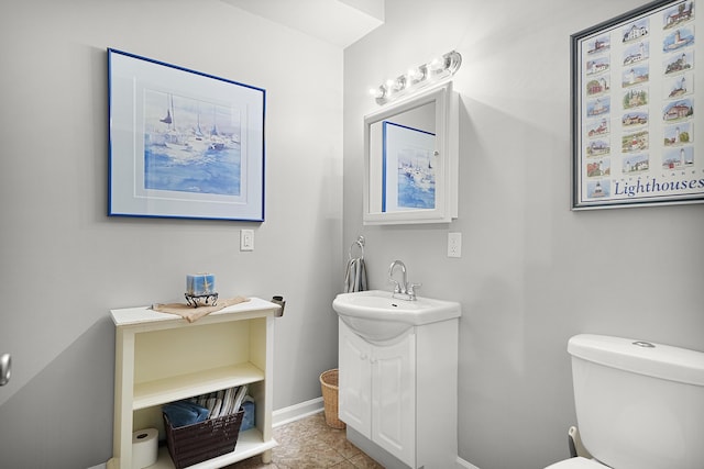 half bathroom featuring vanity, toilet, and baseboards