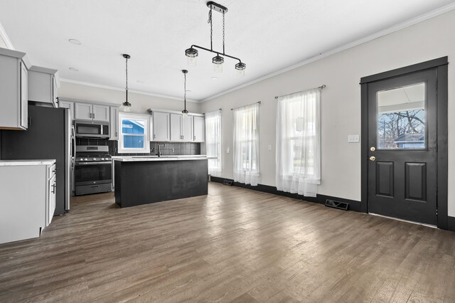 816 7th St, Three Rivers, MI 49093 - kitchen featuring backsplash, a center island, ornamental molding, stainless steel appliances, and dark wood-style flooring