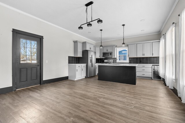 816 7th St, Three Rivers, MI 49093 - kitchen with decorative backsplash, appliances with stainless steel finishes, wood finished floors, and crown molding