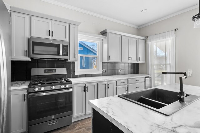 816 7th St, Three Rivers, MI 49093 - kitchen with backsplash, ornamental molding, wood finished floors, stainless steel appliances, and a sink