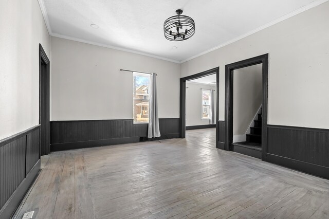 816 7th St, Three Rivers, MI 49093 - empty room with hardwood / wood-style floors, ornamental molding, stairs, wainscoting, and a chandelier