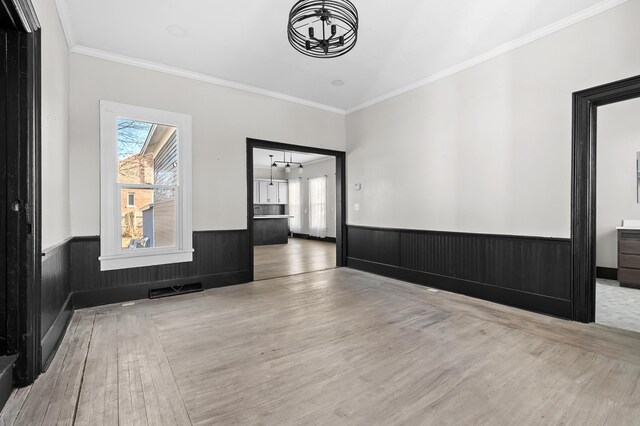 816 7th St, Three Rivers, MI 49093 - empty room with a wainscoted wall, a notable chandelier, wood finished floors, and ornamental molding