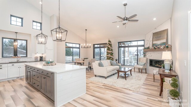 1303 Gallery Pointe Dr, Saline, MI 48176 - kitchen with light wood-style flooring, ceiling fan with notable chandelier, a sink, open floor plan, and white cabinets