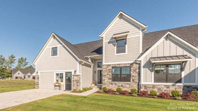 1303 Gallery Pointe Dr, Saline, MI 48176 - view of front of home featuring stone siding, roof with shingles, board and batten siding, concrete driveway, and a front yard