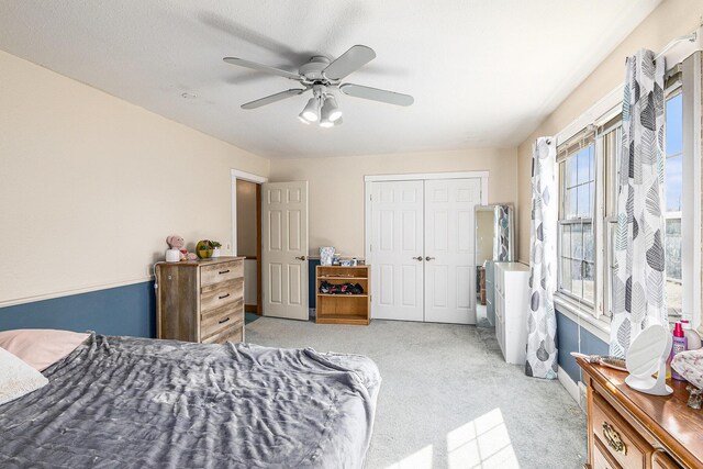 bedroom featuring a ceiling fan, baseboards, a closet, and light colored carpet