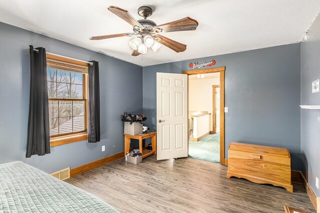 bedroom with visible vents, baseboards, ceiling fan, and wood finished floors