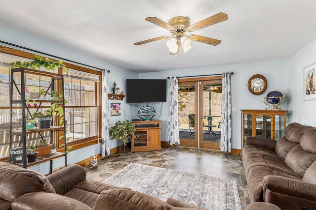 living area with baseboards, ceiling fan, and a textured ceiling