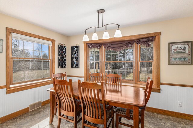 dining room with baseboards, visible vents, and wainscoting