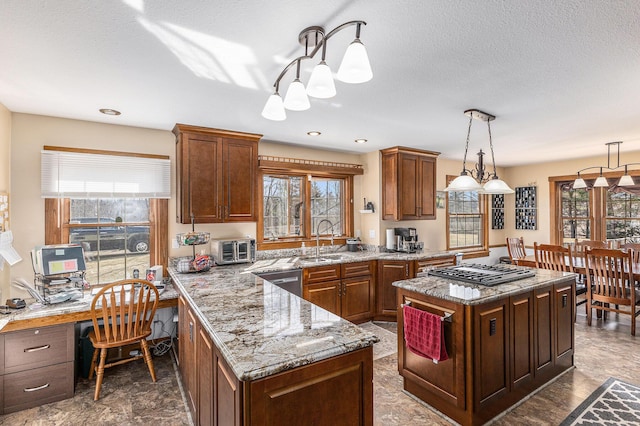 kitchen featuring decorative light fixtures, gas cooktop, stainless steel dishwasher, a sink, and light stone counters