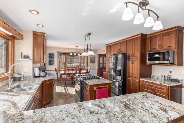 kitchen with a sink, stainless steel appliances, brown cabinetry, and light stone countertops