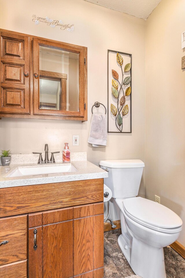 bathroom with toilet, vanity, and baseboards