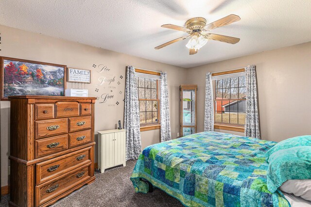 bedroom with dark colored carpet, ceiling fan, and a textured ceiling