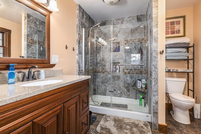 bathroom featuring toilet, a stall shower, and vanity