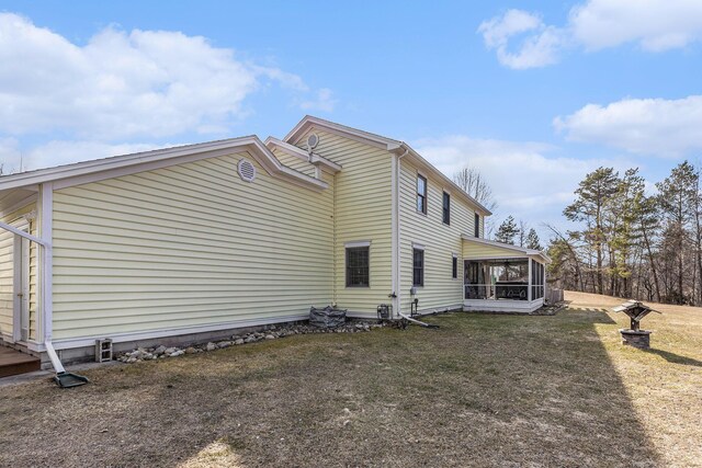 view of home's exterior featuring a sunroom and a lawn