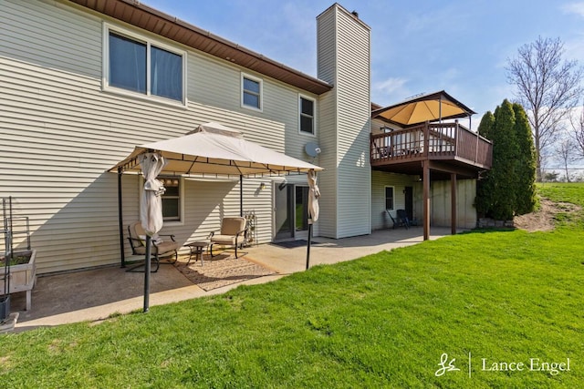rear view of house with a chimney, a lawn, a wooden deck, a gazebo, and a patio