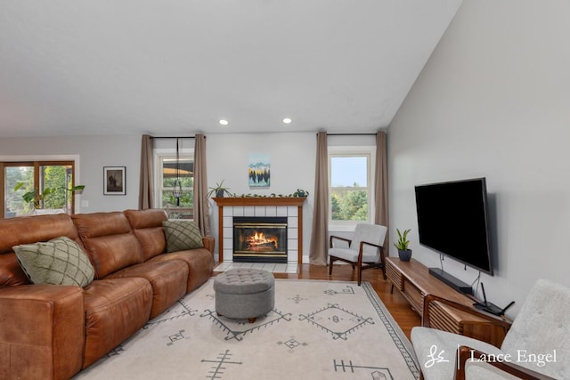 living area with wood finished floors, recessed lighting, a wealth of natural light, and a tile fireplace