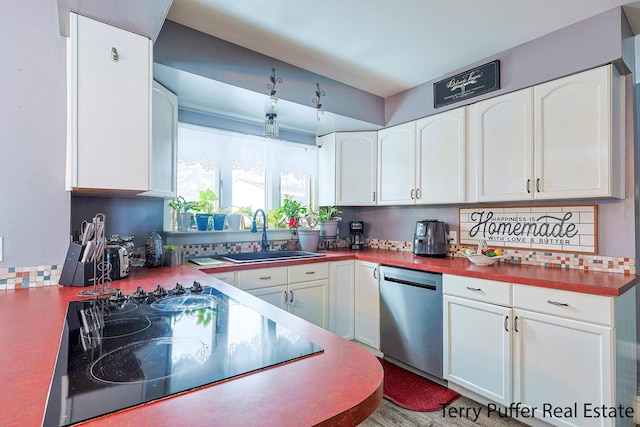 kitchen featuring black electric cooktop, stainless steel dishwasher, a sink, and white cabinetry