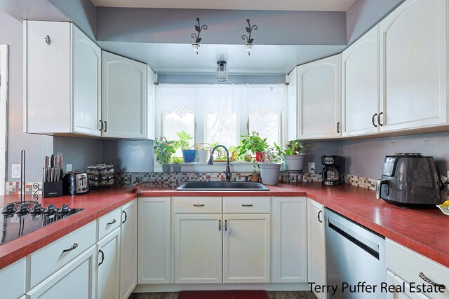 kitchen with stainless steel dishwasher, a sink, tasteful backsplash, white cabinetry, and black electric stovetop