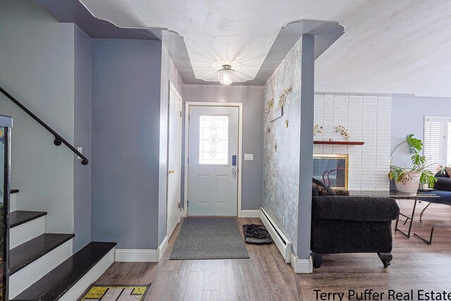 foyer entrance with wood finished floors, stairs, baseboard heating, and a wealth of natural light