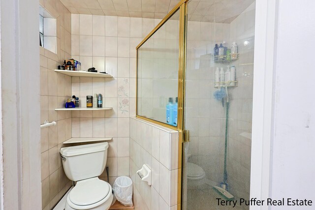full bathroom featuring a shower stall, tile walls, and toilet
