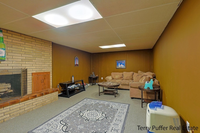 carpeted living area featuring a brick fireplace and a drop ceiling