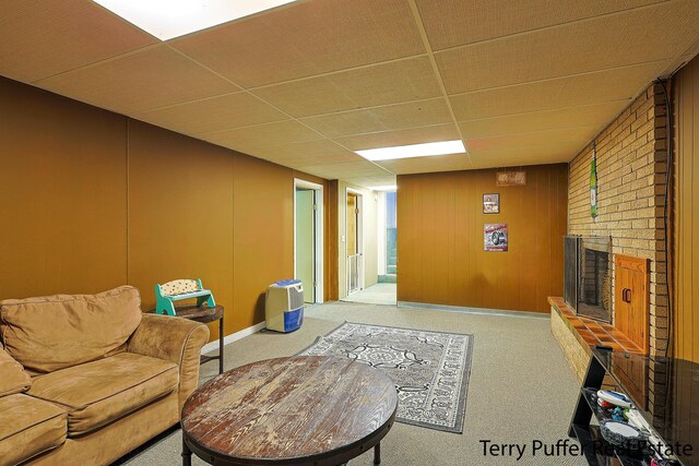 carpeted living room featuring a fireplace and a paneled ceiling