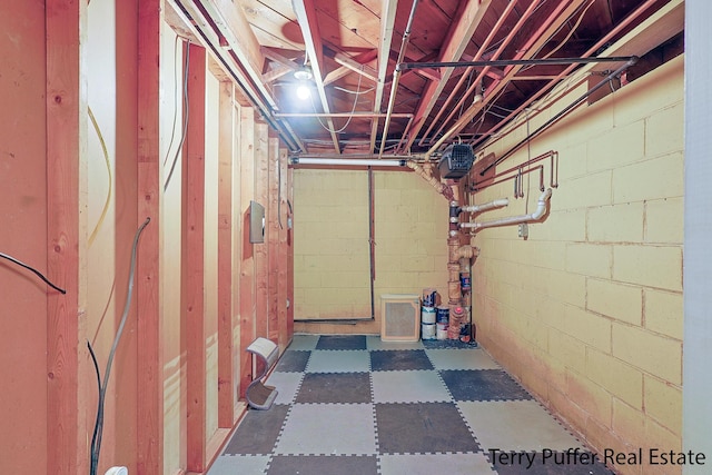 unfinished basement with concrete block wall and tile patterned floors