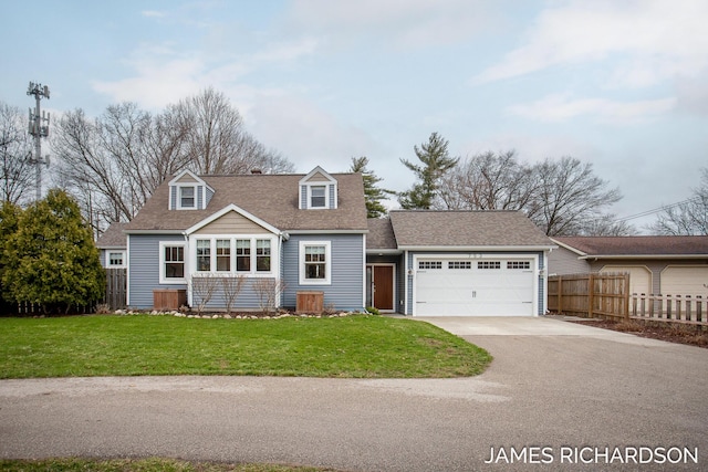 cape cod home featuring a garage, driveway, a shingled roof, fence, and a front yard