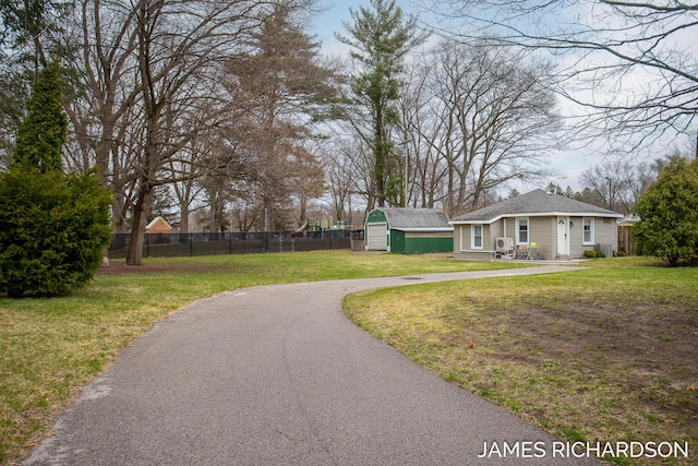 exterior space featuring an outbuilding, a shed, a front yard, and fence