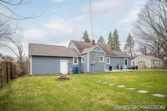 back of house featuring an outdoor fire pit, fence, a yard, a wooden deck, and roof with shingles