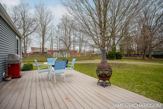 wooden terrace with a fenced backyard, outdoor dining area, a grill, and a lawn
