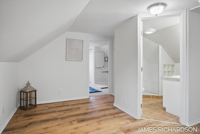 bonus room featuring baseboards, lofted ceiling, and light wood-type flooring