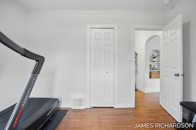 exercise area with wood finished floors, visible vents, and baseboards