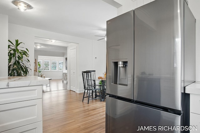 kitchen featuring light wood-style floors, ceiling fan, stainless steel fridge with ice dispenser, white cabinets, and baseboards