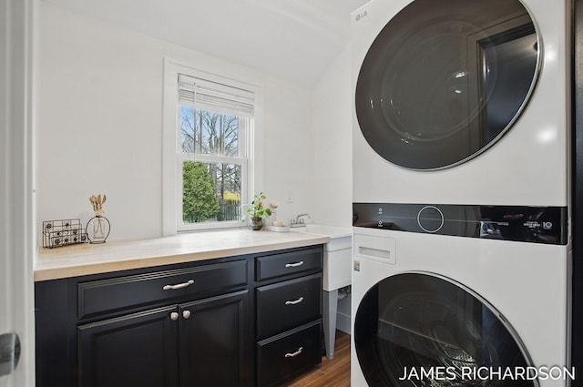 washroom with stacked washer / dryer, dark wood-type flooring, and cabinet space