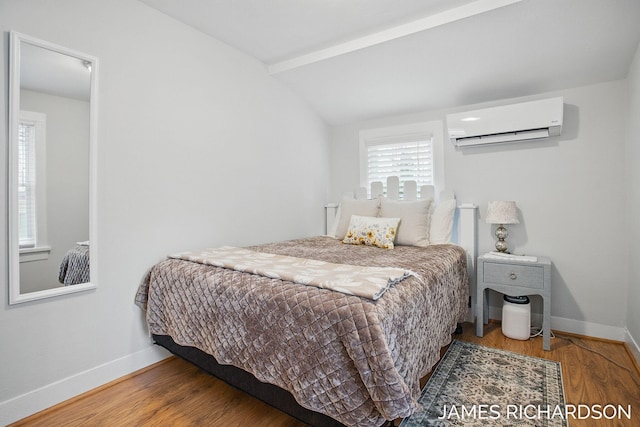 bedroom featuring vaulted ceiling, an AC wall unit, baseboards, and wood finished floors