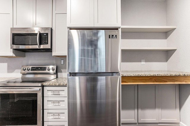 62711 Balk Rd, Sturgis, MI 49091 - kitchen with appliances with stainless steel finishes, open shelves, and light stone counters