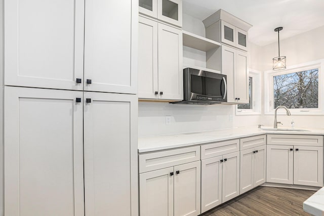 62711 Balk Rd, Sturgis, MI 49091 - kitchen featuring a sink, stainless steel microwave, light stone countertops, decorative light fixtures, and glass insert cabinets