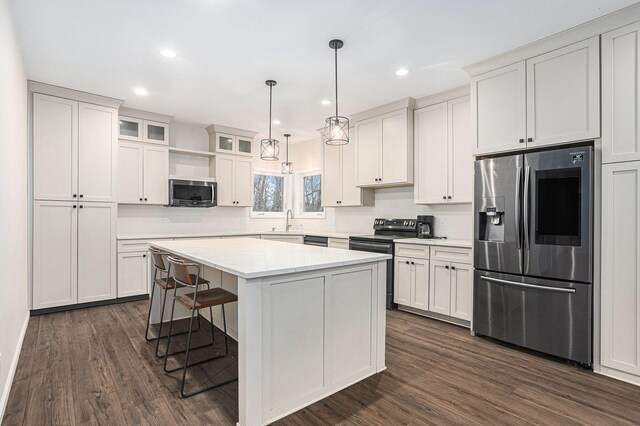 62711 Balk Rd, Sturgis, MI 49091 - kitchen featuring appliances with stainless steel finishes, dark wood-type flooring, a kitchen island, a kitchen bar, and recessed lighting