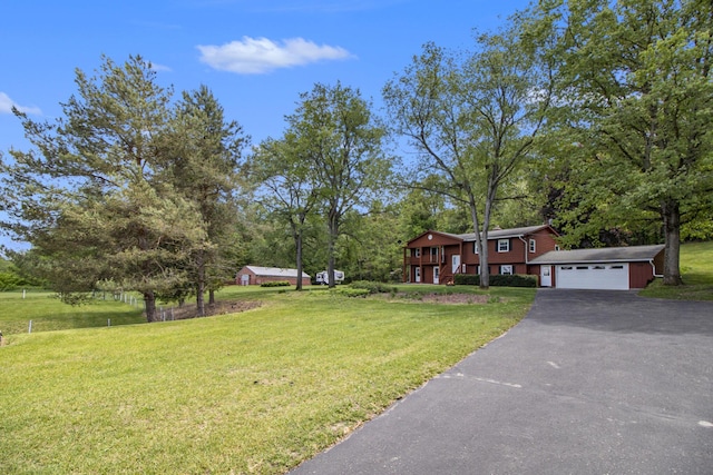 view of front of house with driveway, a front yard, a garage, and an outbuilding