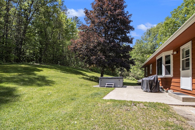 view of grassy yard featuring a hot tub and a patio area
