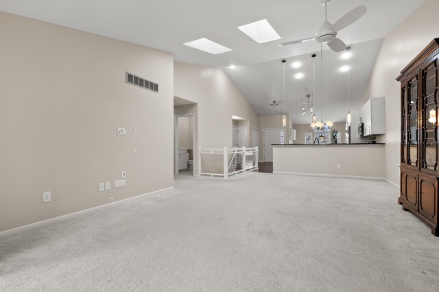 unfurnished living room with ceiling fan, light carpet, high vaulted ceiling, a skylight, and visible vents