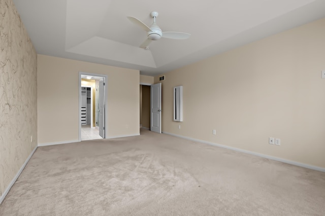 unfurnished bedroom with a raised ceiling, baseboards, carpet flooring, and visible vents