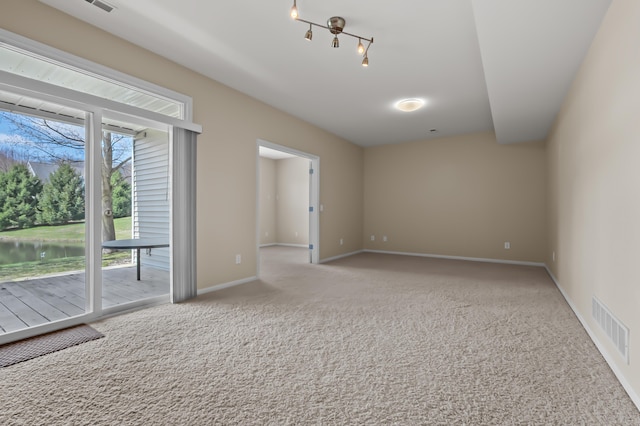 spare room featuring visible vents, carpet, a water view, and baseboards