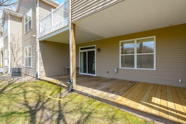 rear view of property featuring a balcony, central AC, a yard, and a wooden deck