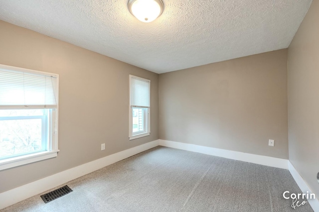spare room featuring baseboards, carpet floors, visible vents, and plenty of natural light