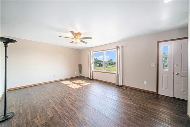 interior space featuring a ceiling fan, dark wood-type flooring, and baseboards
